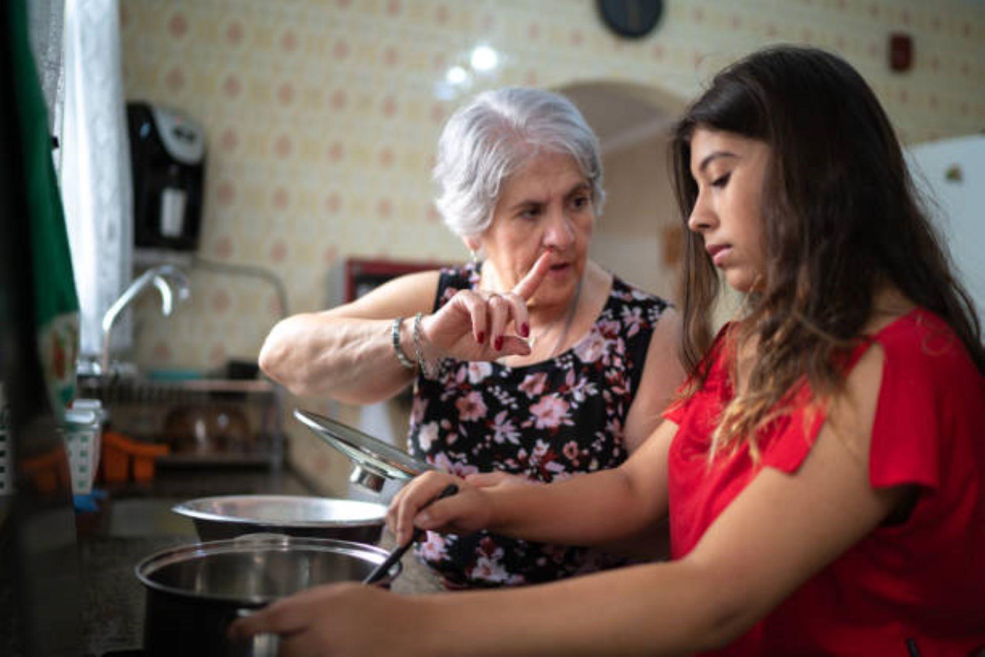 Grandmother teaching her granddaughter how to cook.