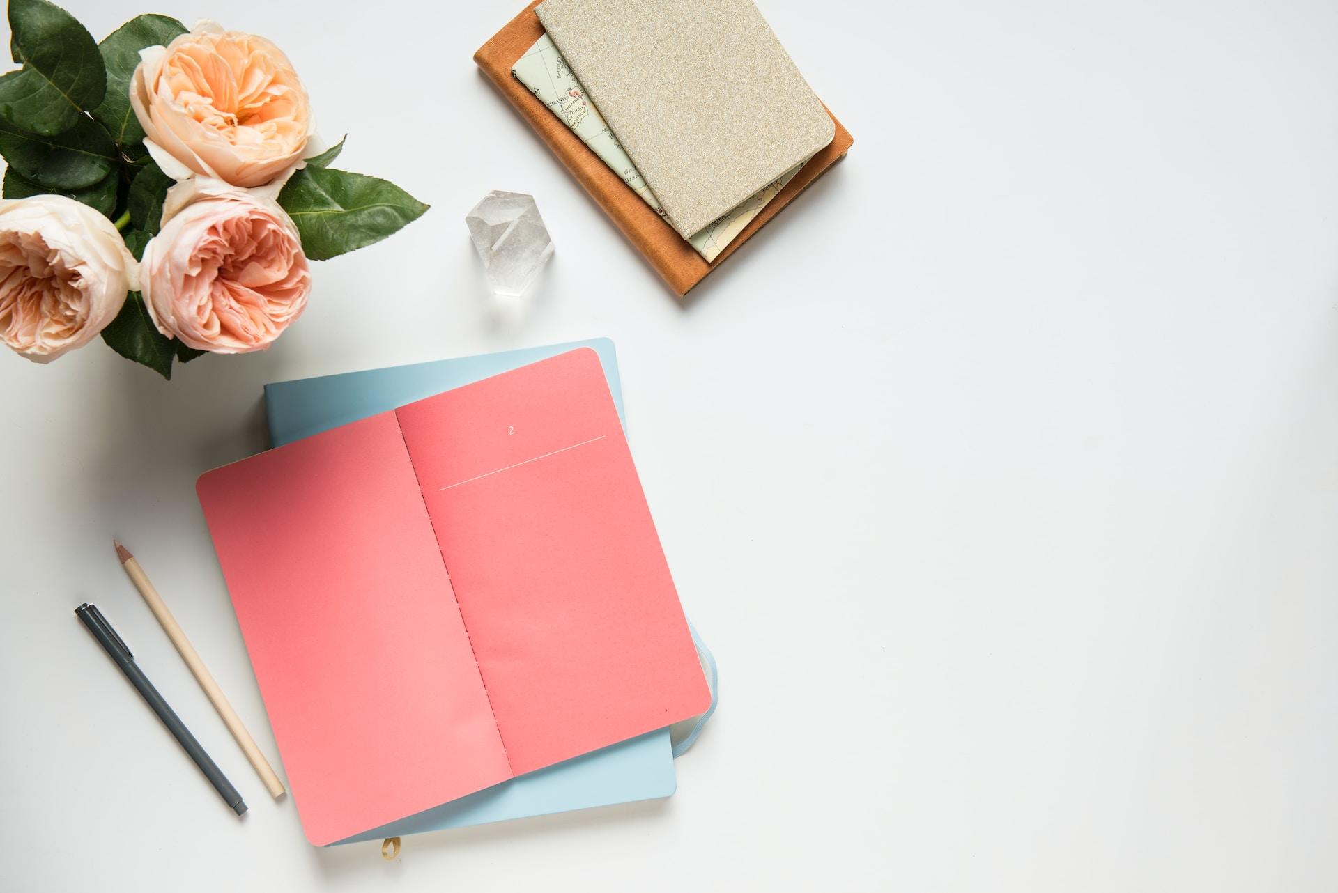A pink notebook on a white desk.