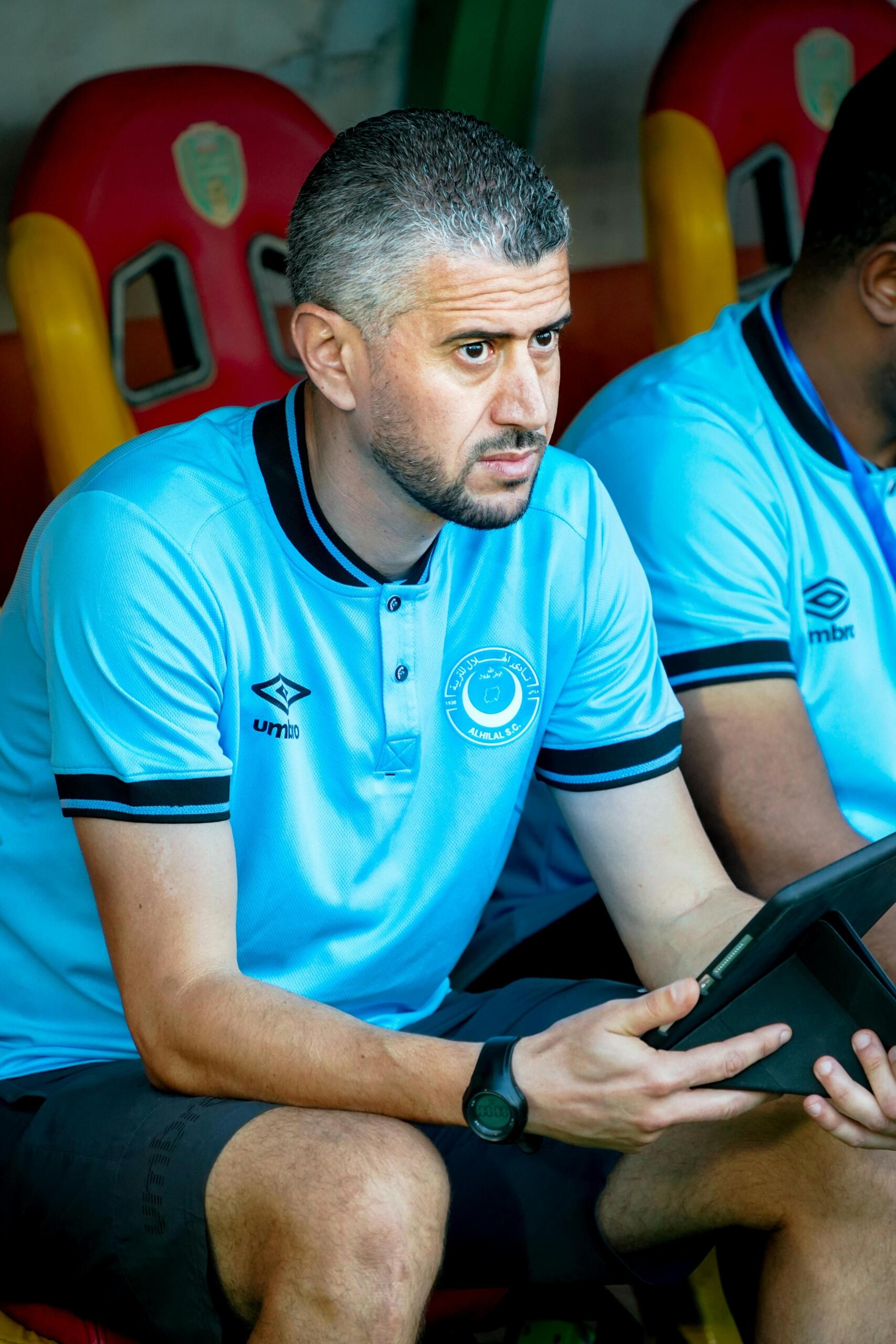 A football coach analyzing a game on a tablet, reviewing plays or strategies.