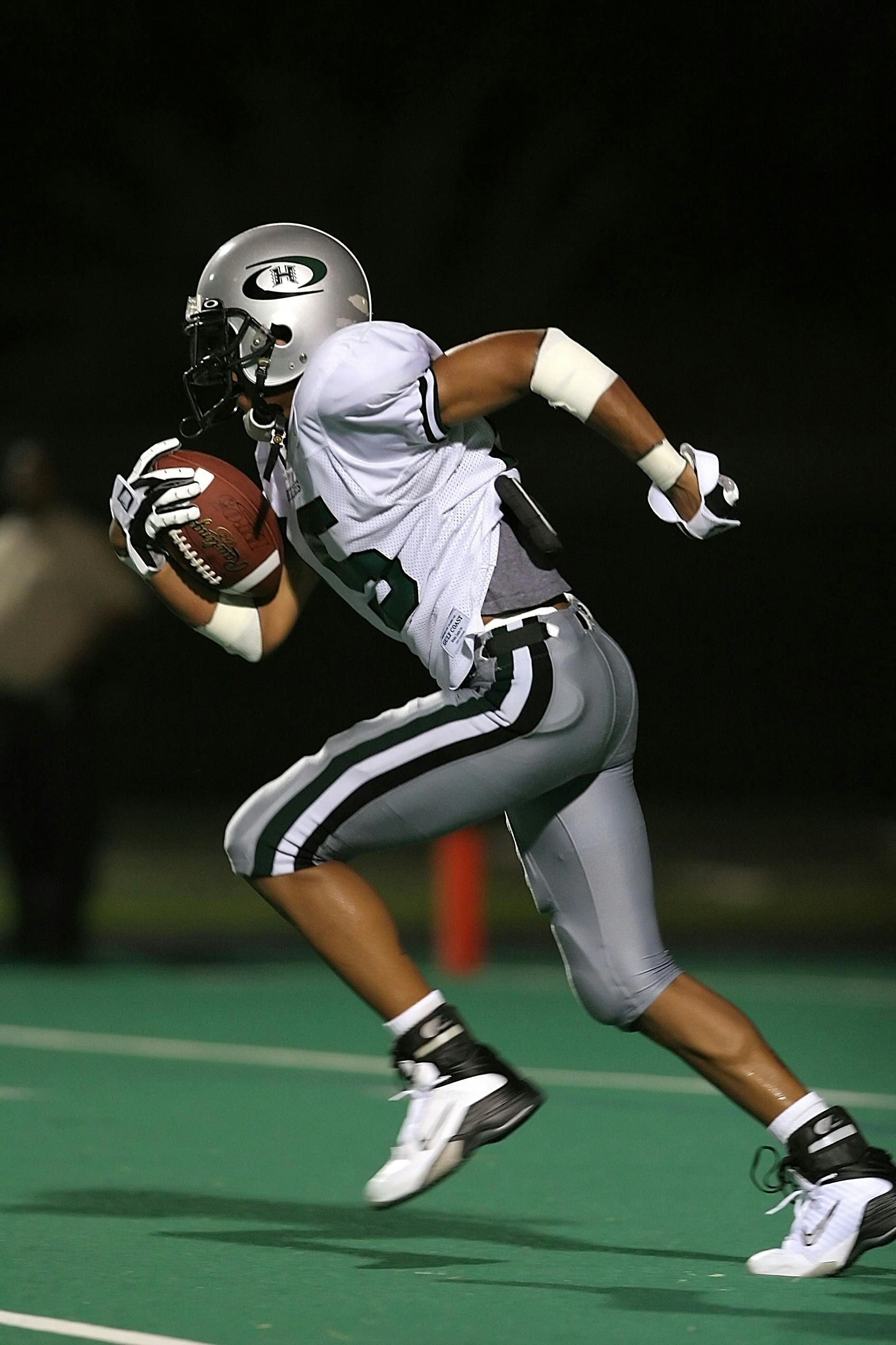 Football player holding a football in his hands, while in play.