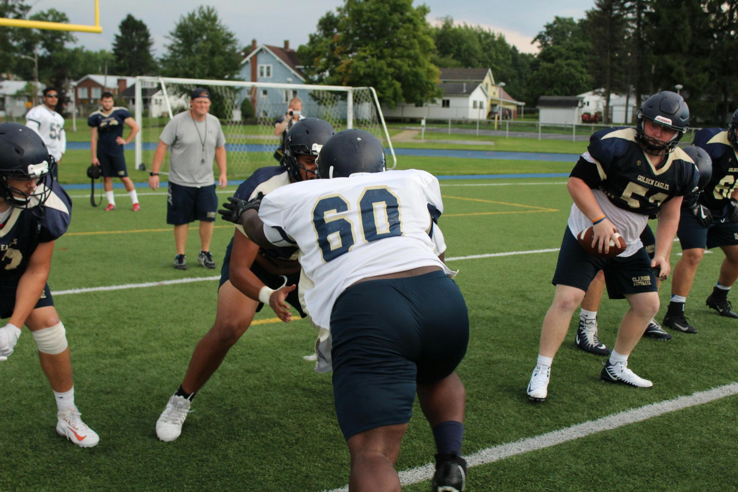 Group of men actively playing football on a green field.
