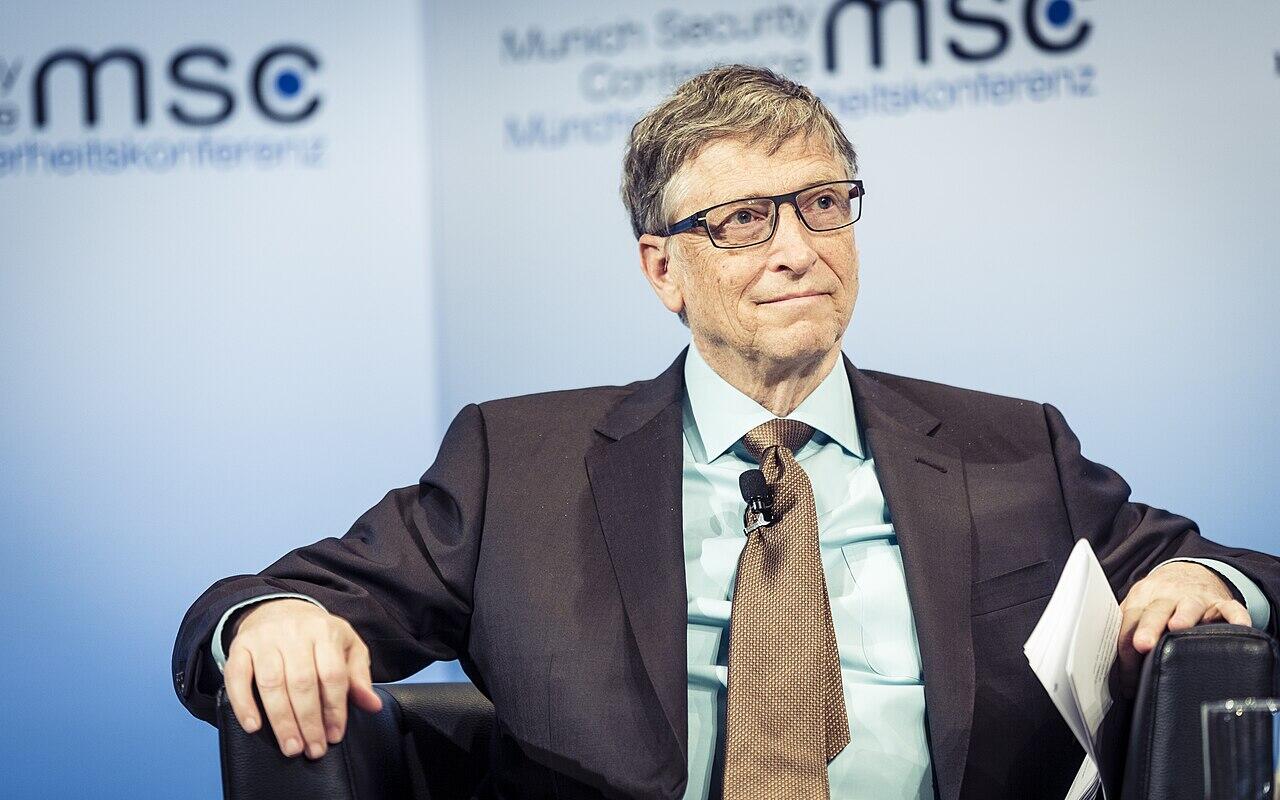 Bill Gates sitting in a suit during a conference.