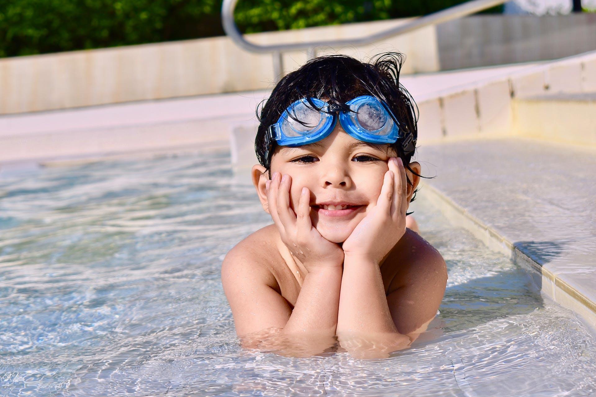 A child lays on their stomach in the very shallow part of a pool.