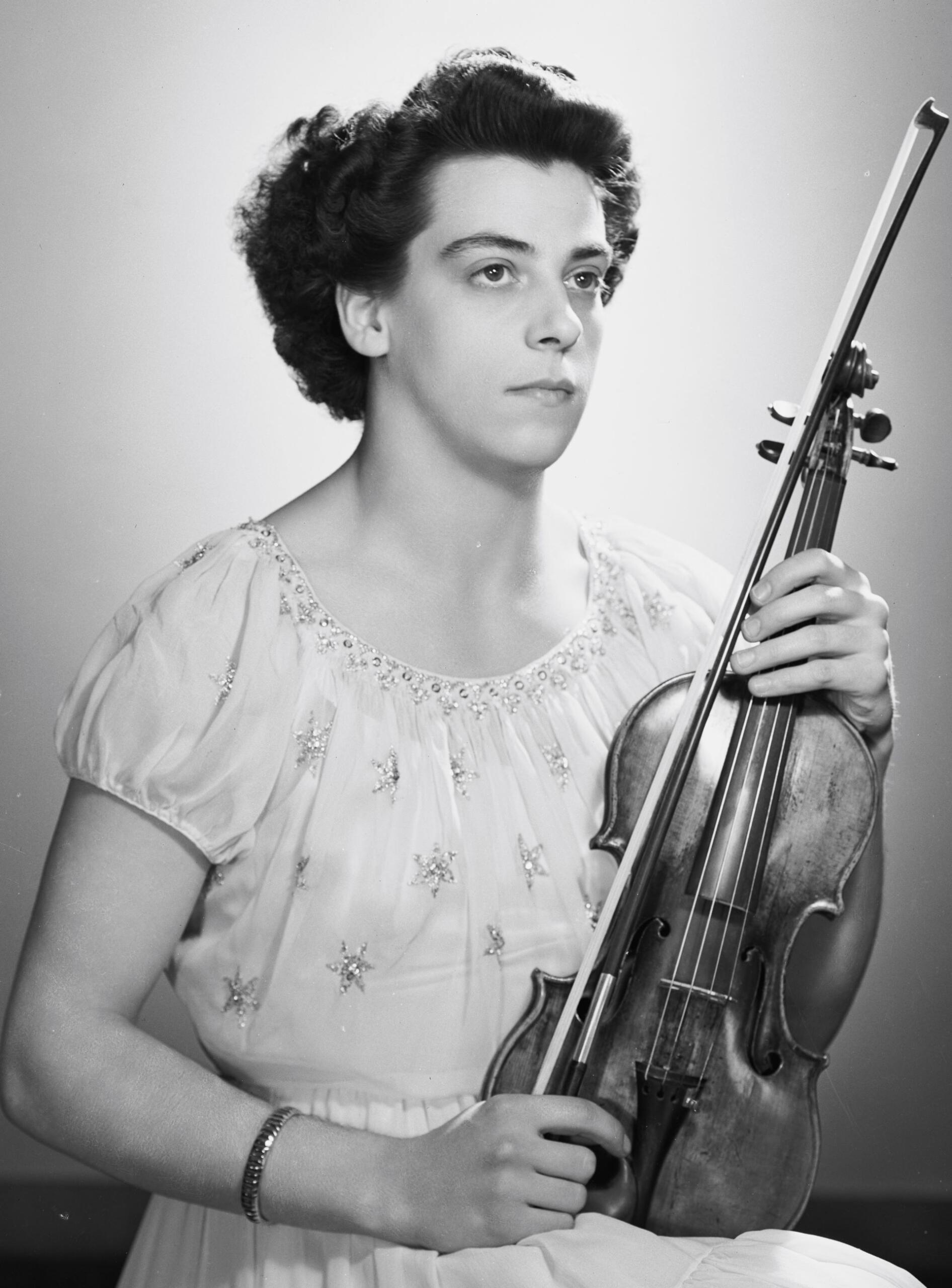 Black and white portrait of a woman holding a violin and bow, looking slightly to the side.