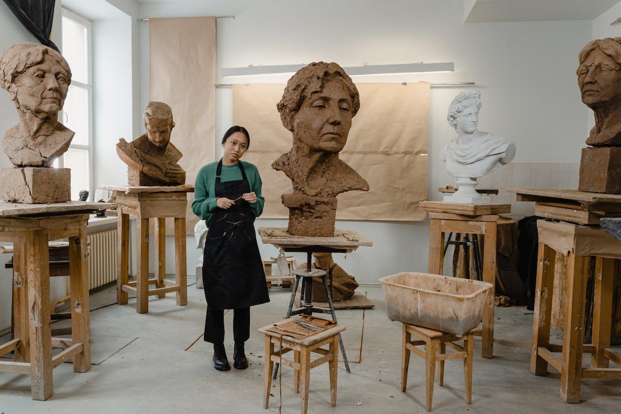 A sculptor in a studio filled with large clay busts
