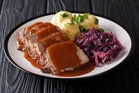 Sauerbraten with sauce, mashed potatoes, and cabbage.