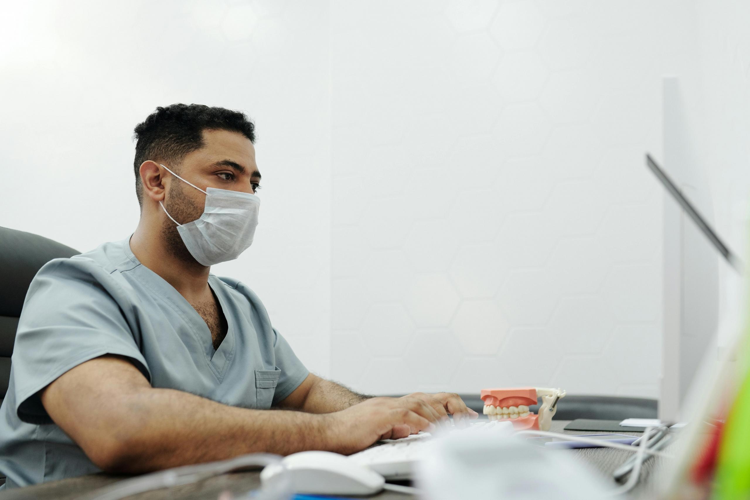 A nurse wearing a mask at the desk.