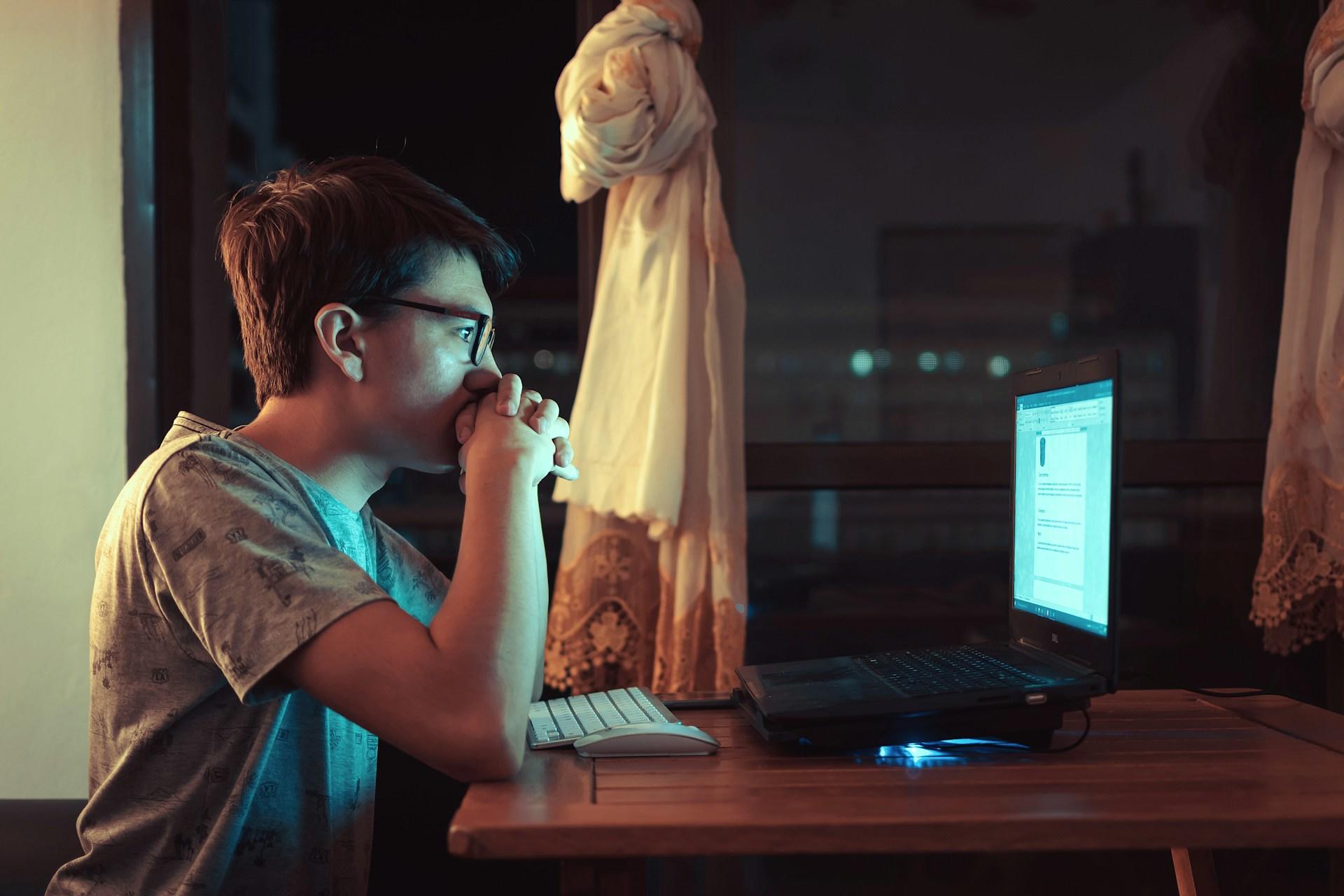 A person staring at a computer screen while writing.
