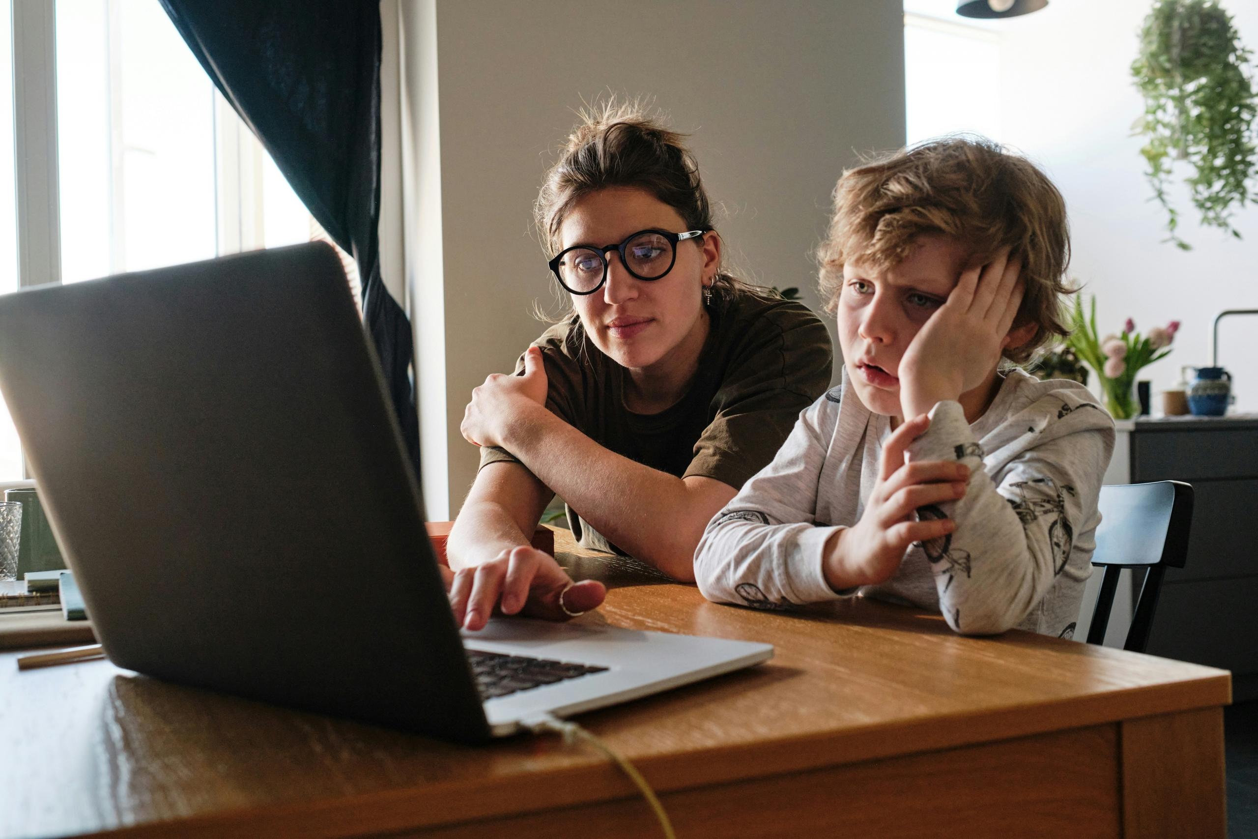 A lady tutoring a boy for school/
