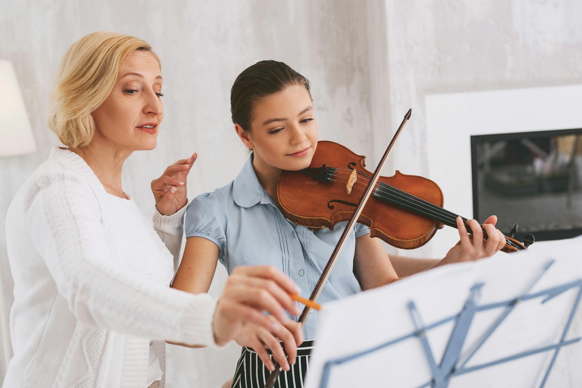 A tutor helping a student learn to play the violin.