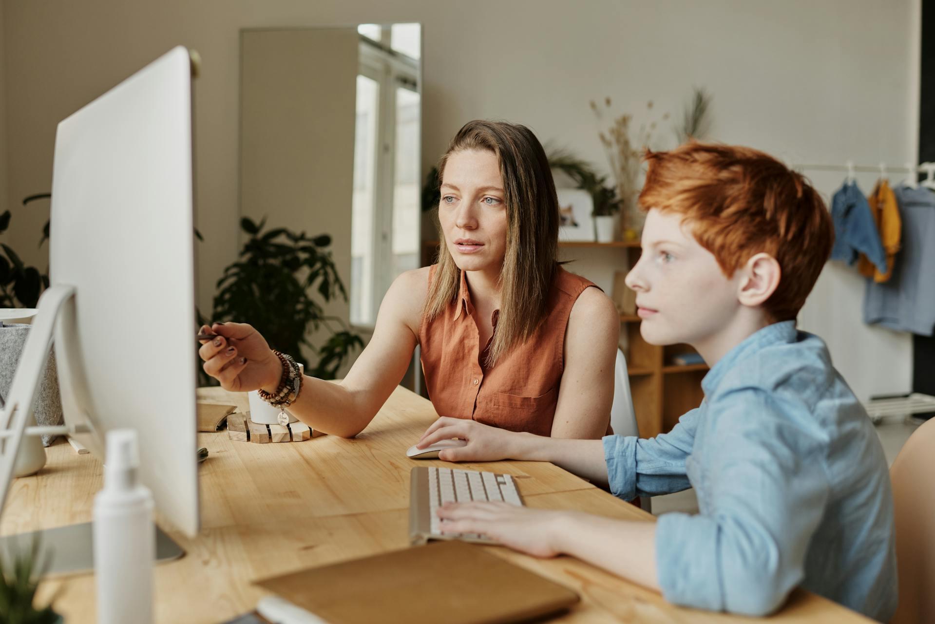 A tutor helping a young student on the computer.