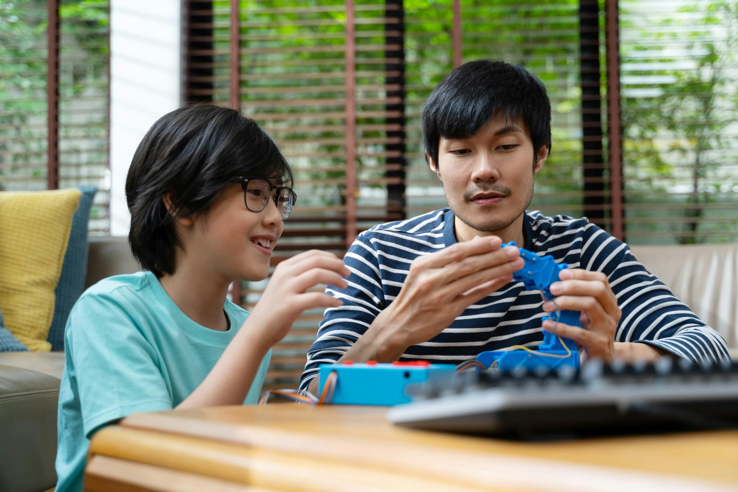 A tutor teaching a young boy about robotics.