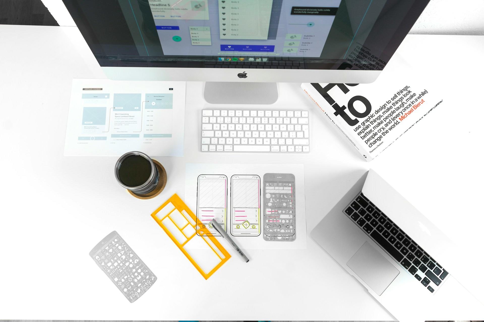 A top-down view of sketches of a phone, a laptop, desktop computer, graphic design book, and graphic design tools.