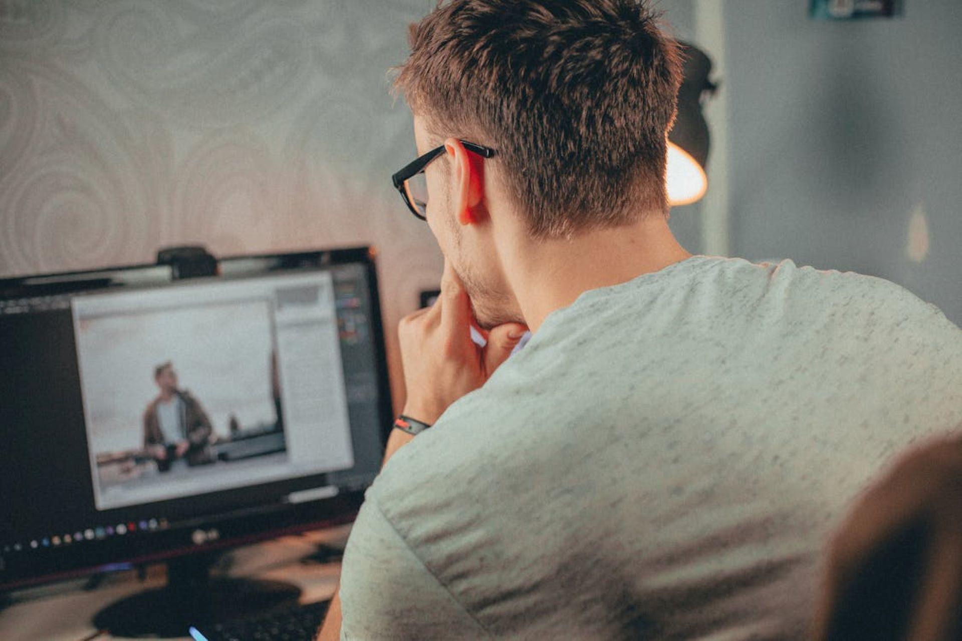 A man sitting in front of a computer screen with image display.
