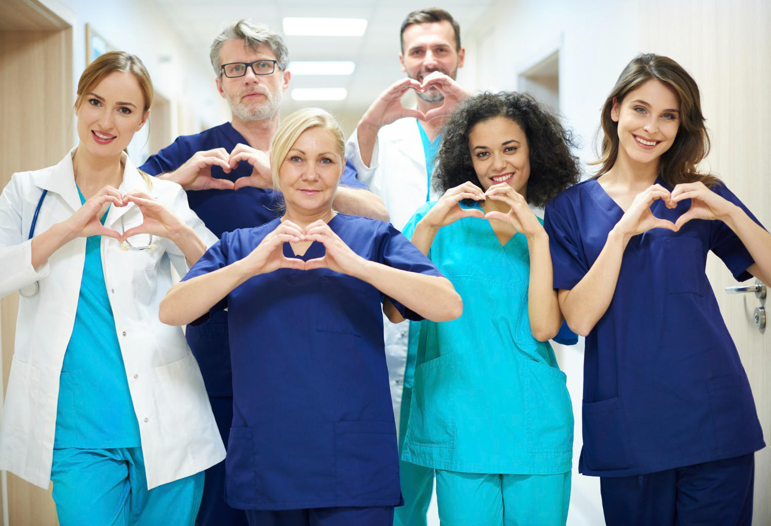 A group of six nurses making hearts with their hands.