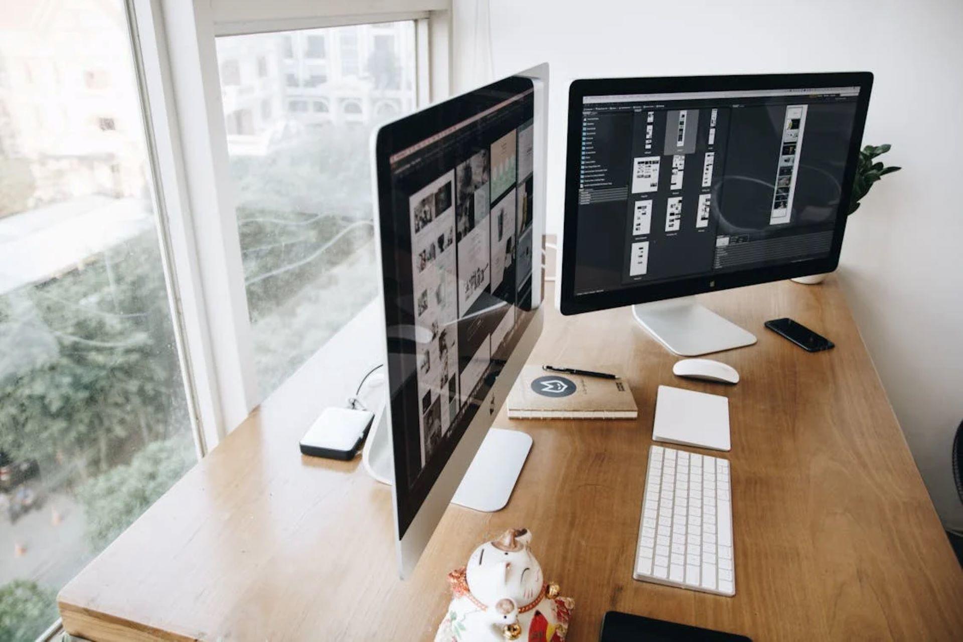 Two computer monitors displaying design software on a desk 