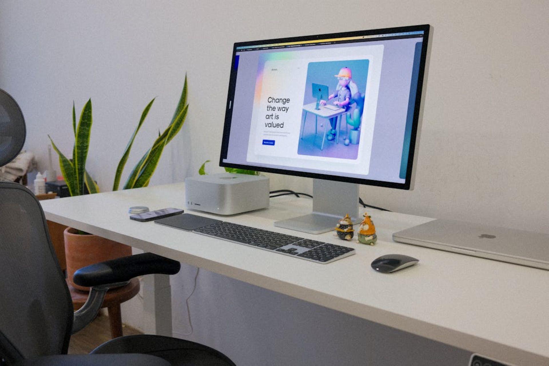 A desk with a computer displaying a graphic design