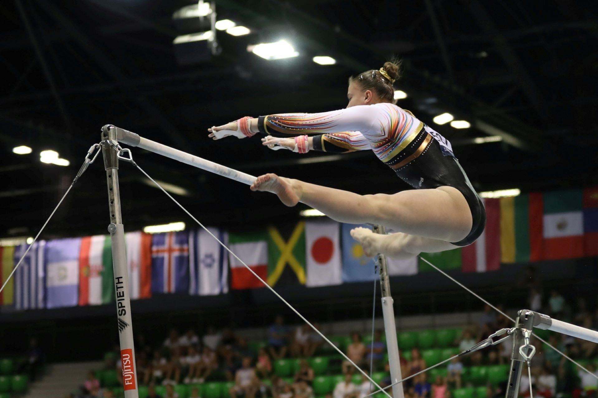 A gymnast mid-air during a uneven bars routine