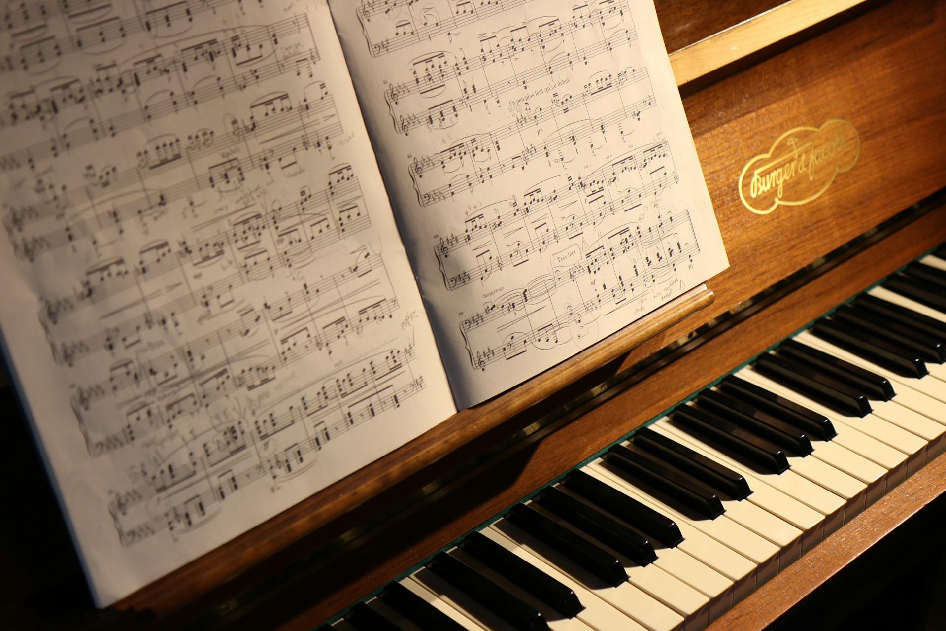 A piano with sheet music on the music stand.