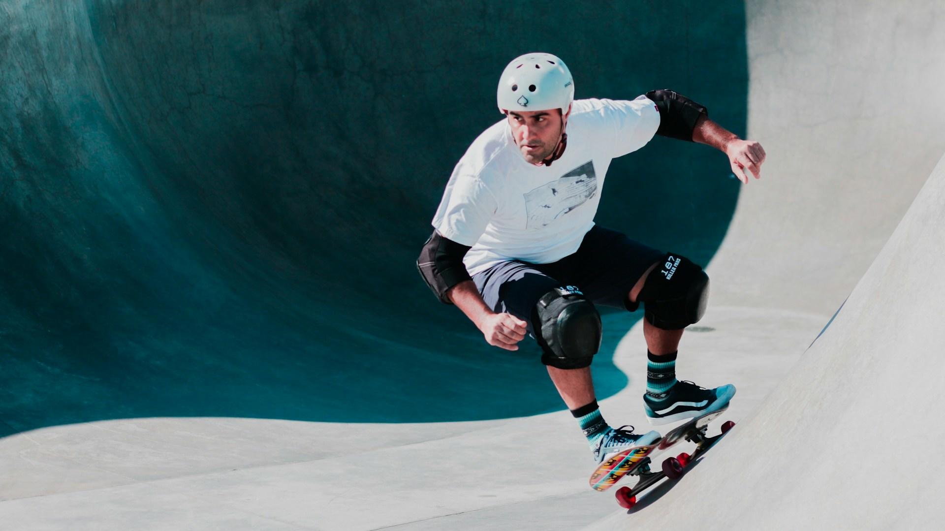 A skateboarder wearing safety gear and skating in a half pipe