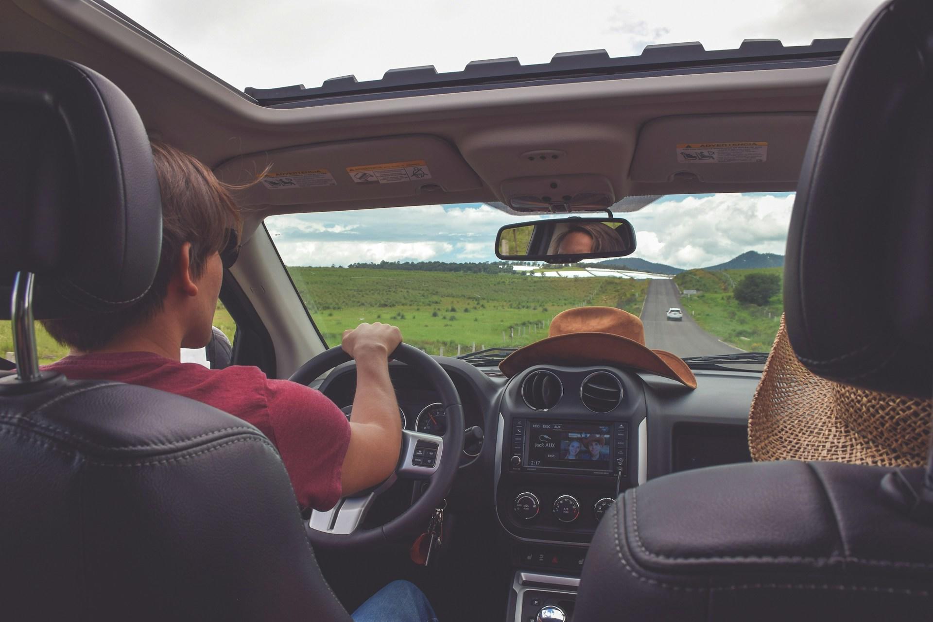 A teen driving a car through the countryside