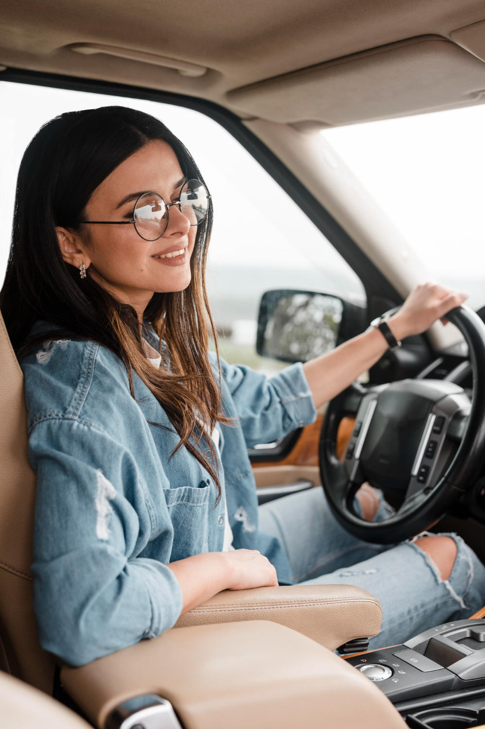 Young woman with glasses sitting in the driver's seat of a car