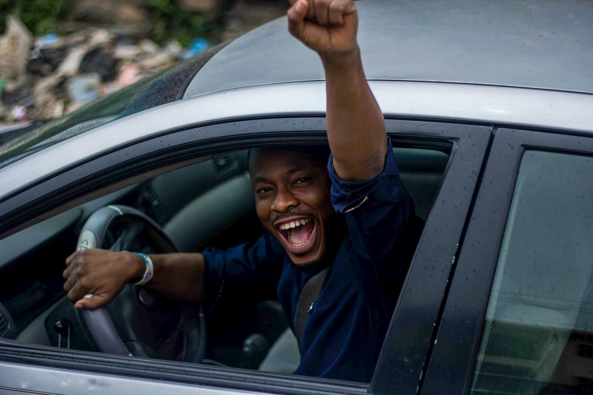 A teen cheering in the river's seat of a car