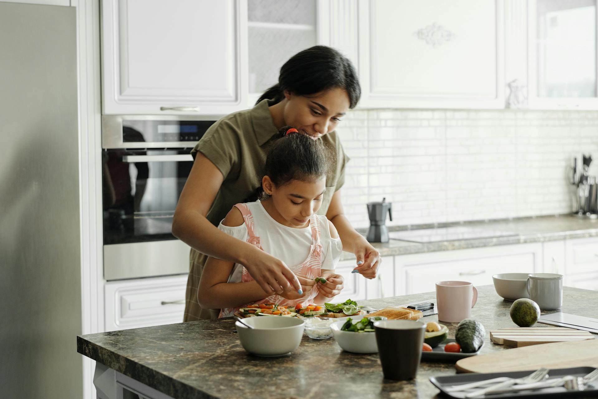 A mom and daughter cooking in the kitchen.