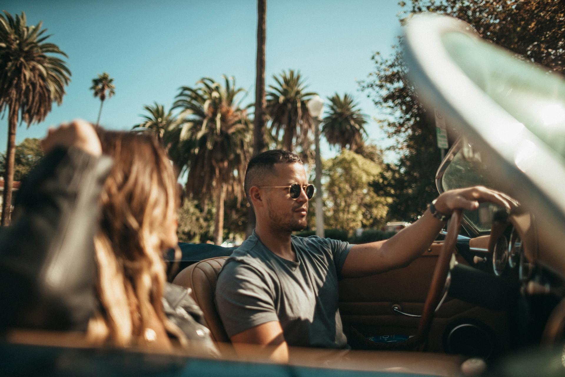 a couple in a convertible driving in Los Angeles near palm trees