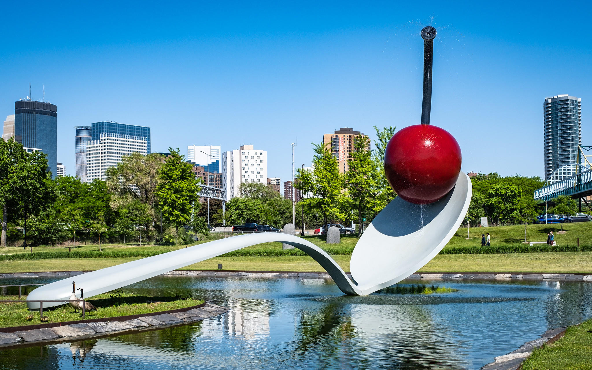 A giant spoon with a cherry on top in the city.