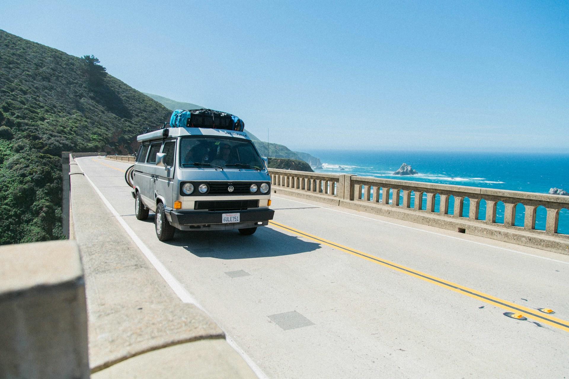 A van driving on a road in Big Sur, California, near the mountains and the ocean