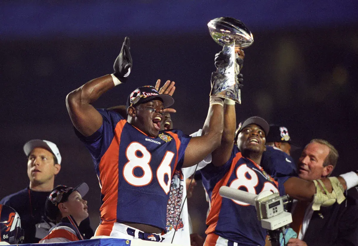 Broncos team members holding up the Super Bowl trophy in 1998