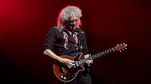 Brian May playing the guitar on stage.