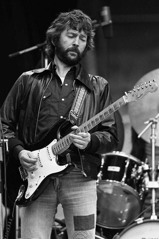 Eric Clapton performing the guitar on stage.