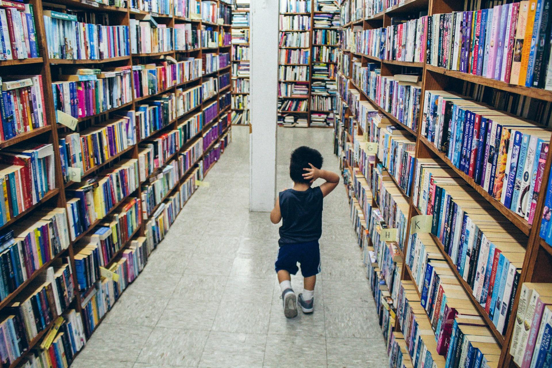 A young boy walking in a library.