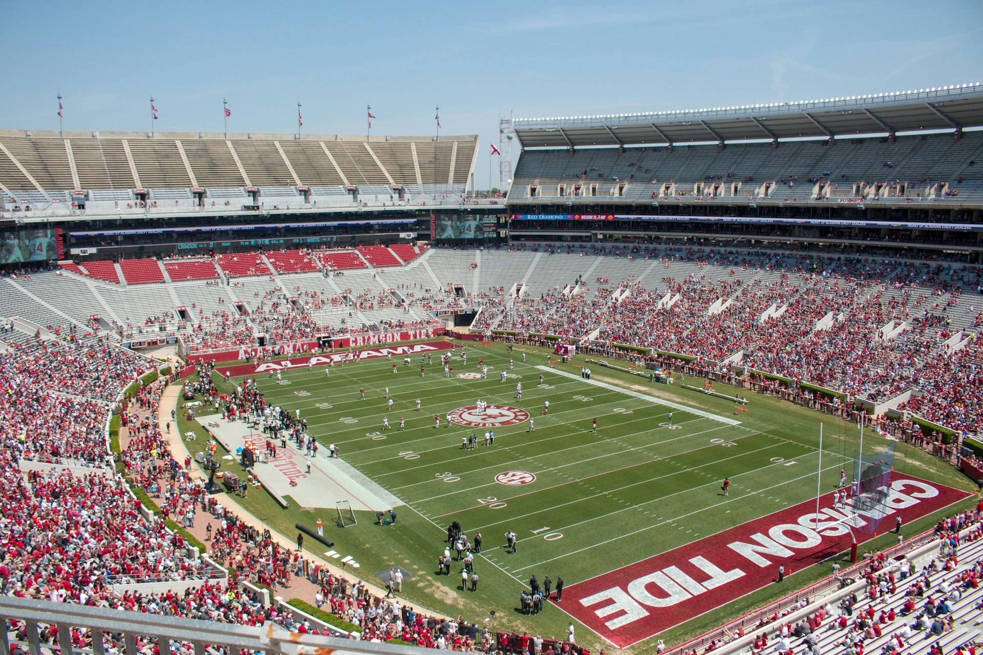 a wide shot of Alabama's football field which shows many fans in the stands and the words "Alabama" and :Crimson Tide" in the end zones