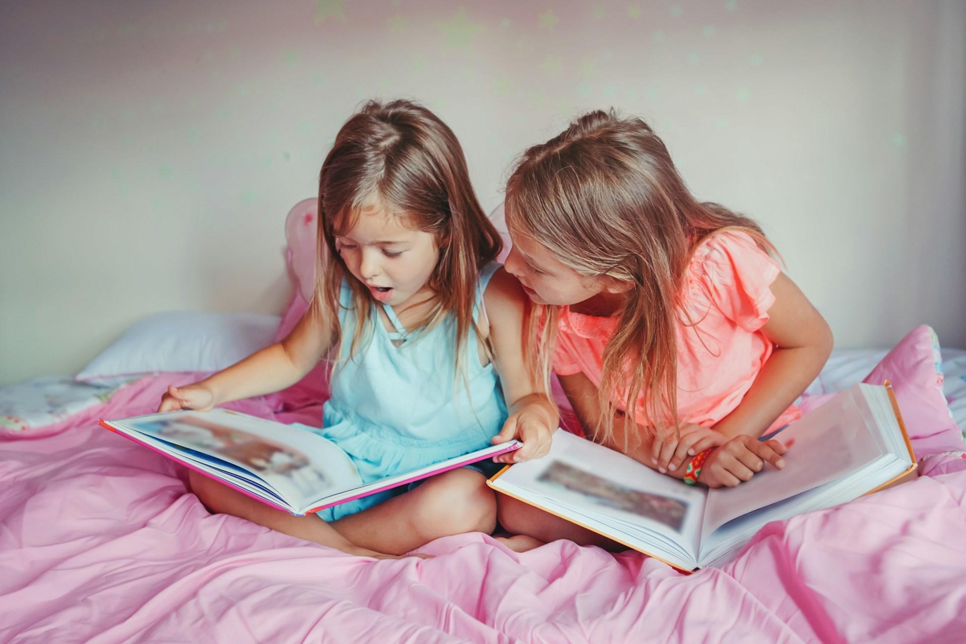 Two girls reading on their bed.