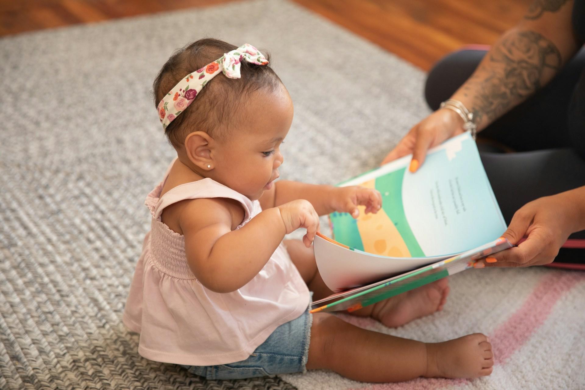 A young toddler reading with her mother.