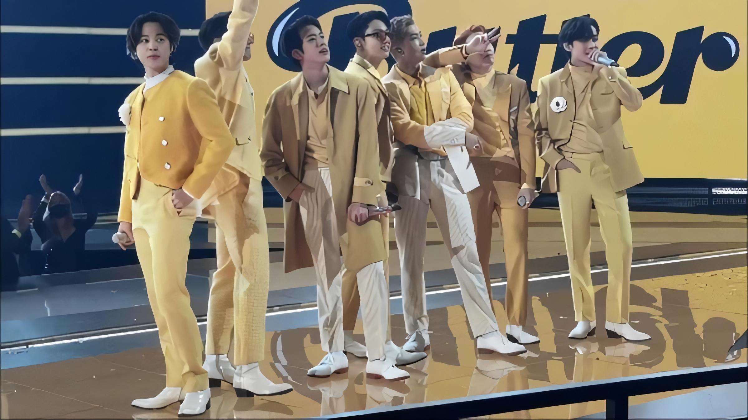 BTS members on stage dressed in coordinating yellow outfits for the song "Butter"