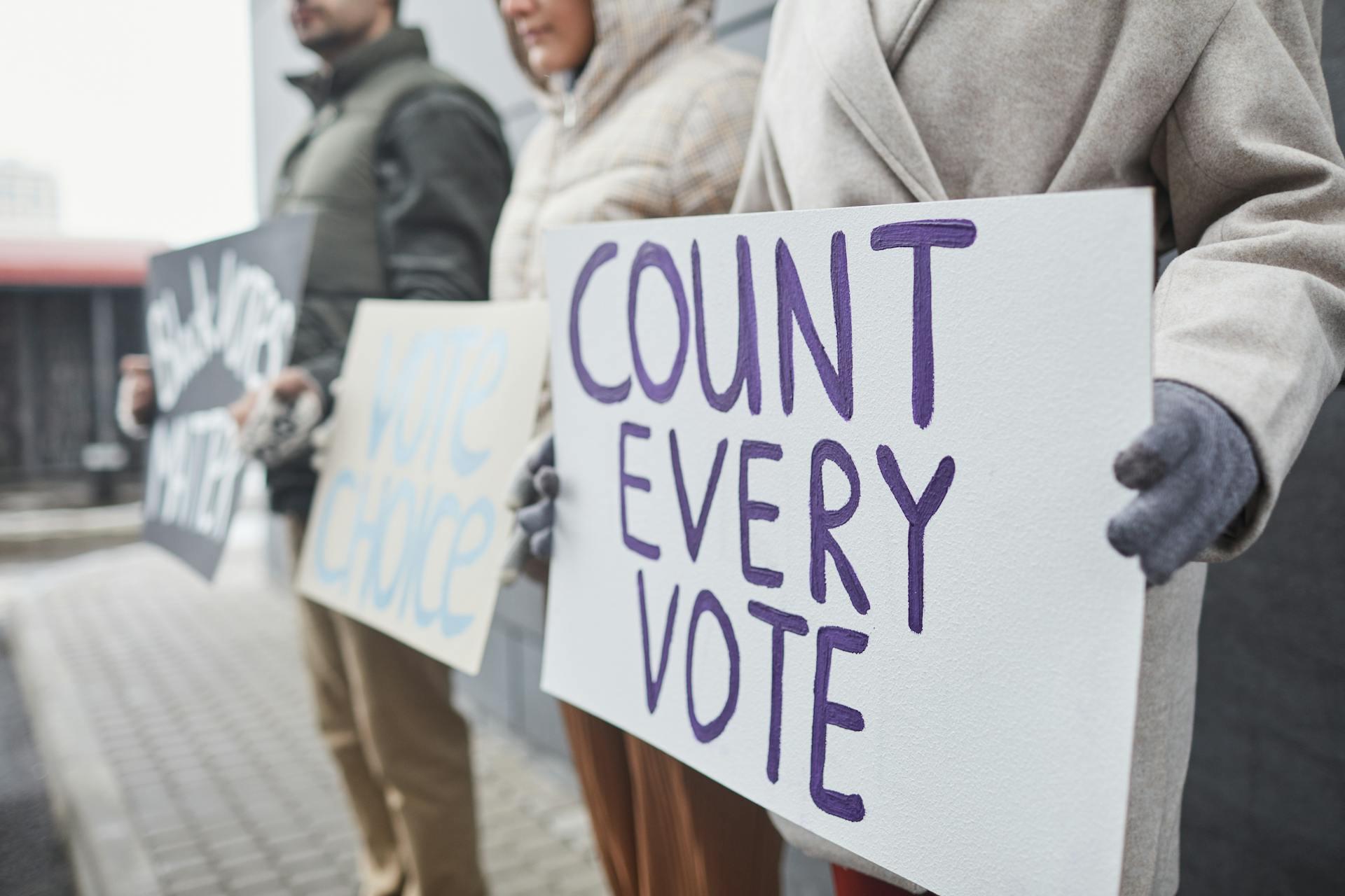 activists holding signs about voting, especially one that says 