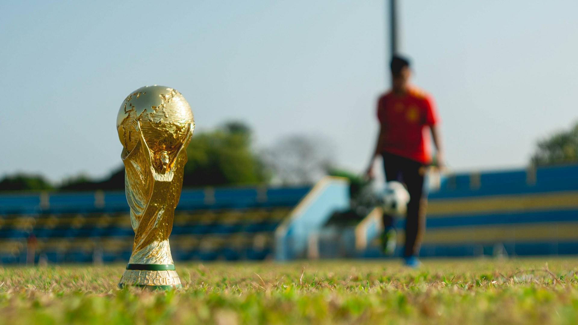A soccer ball and a trophy on a field.