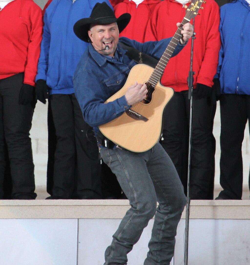 Garth Brooks playing the guitar on stage.