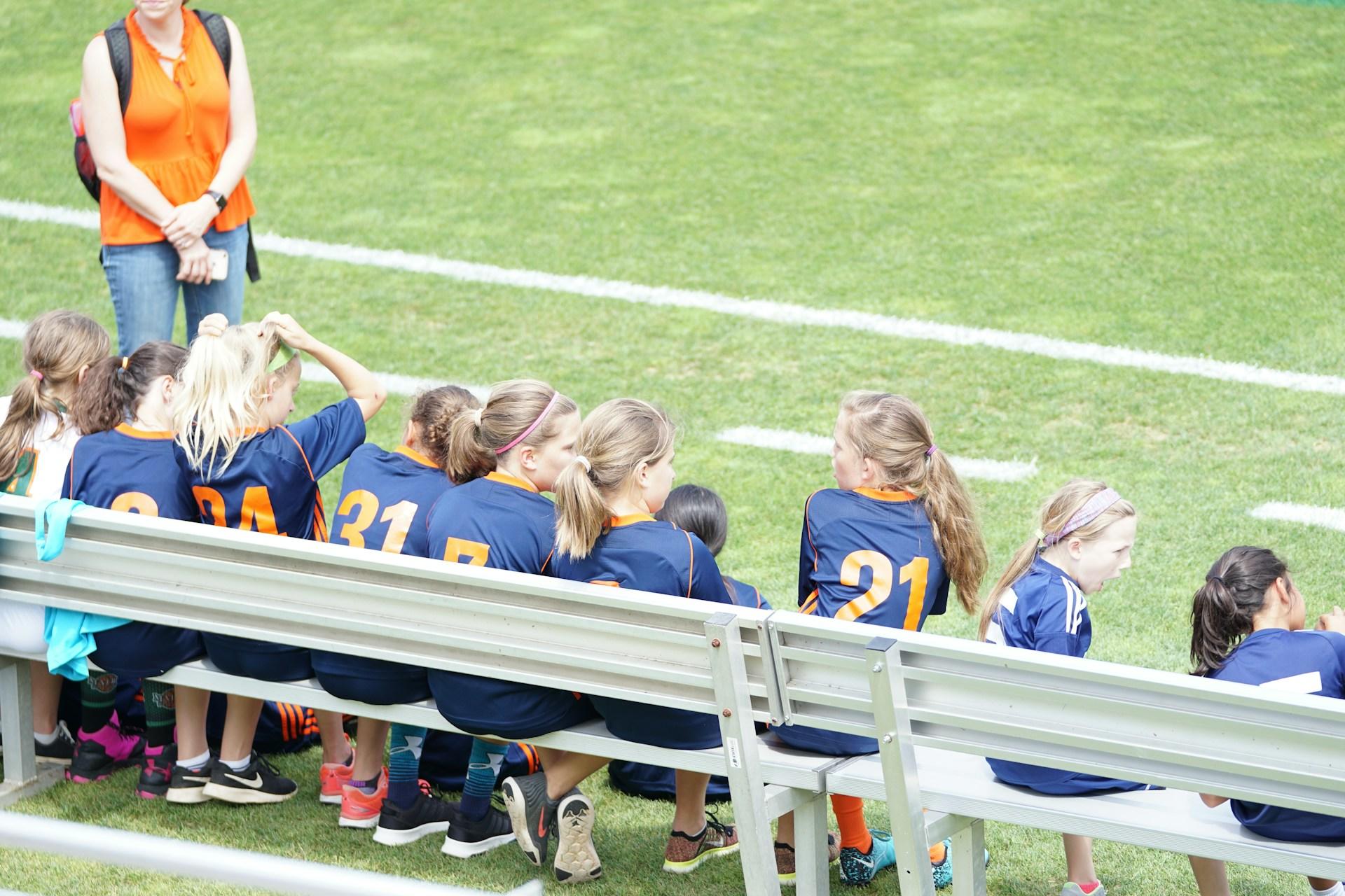 A girl's soccer team on the bench.