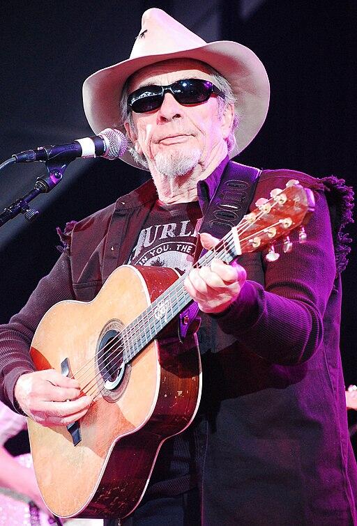 Merle Haggard playing the guitar on stage.