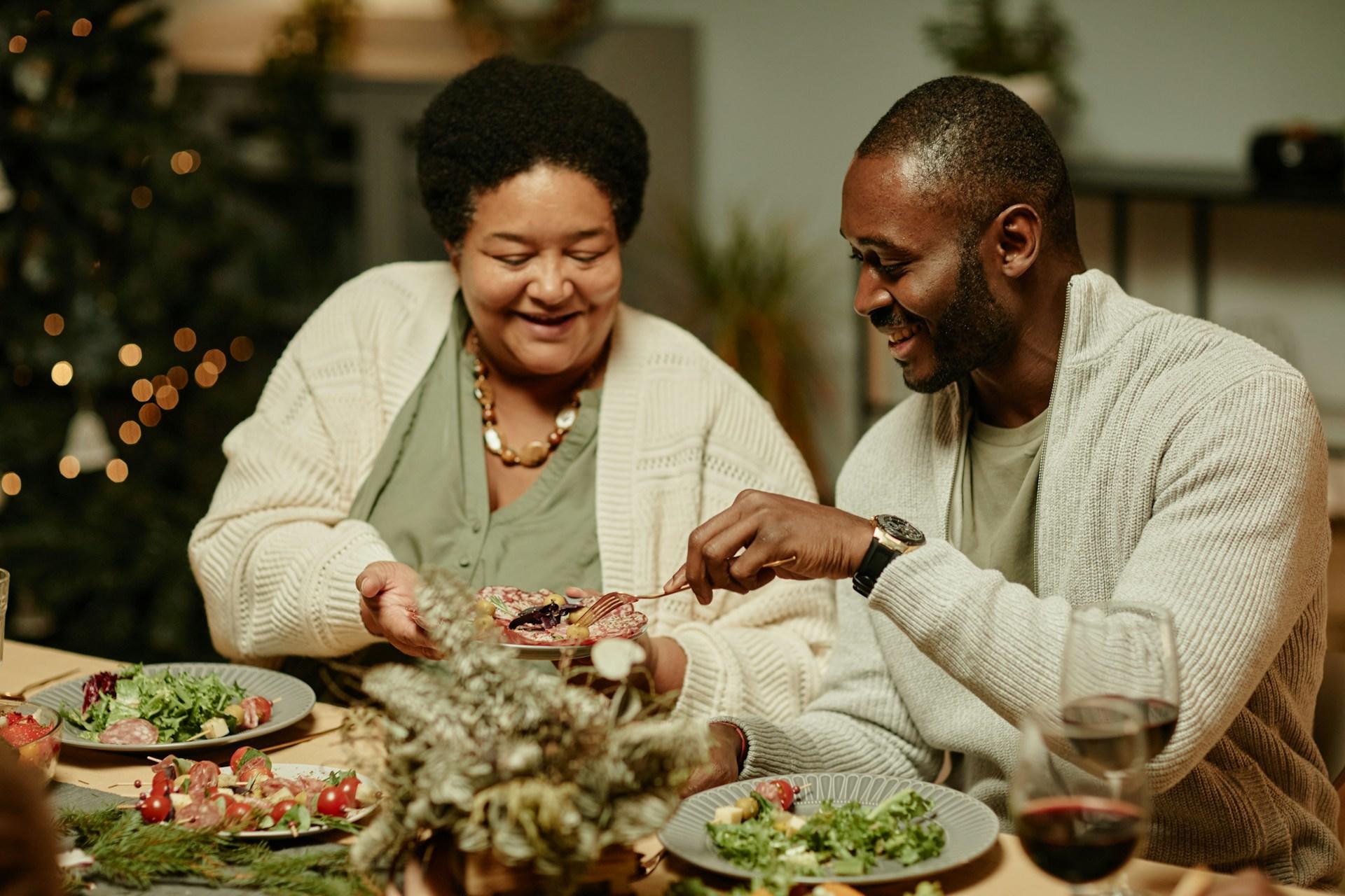 Two people passing food around the table