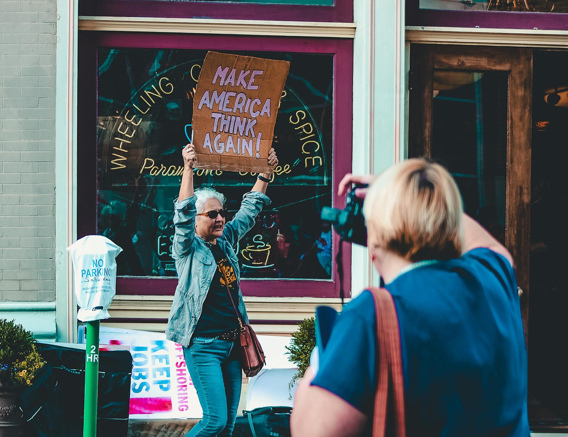 A protester holding a sign that says "make America think again."