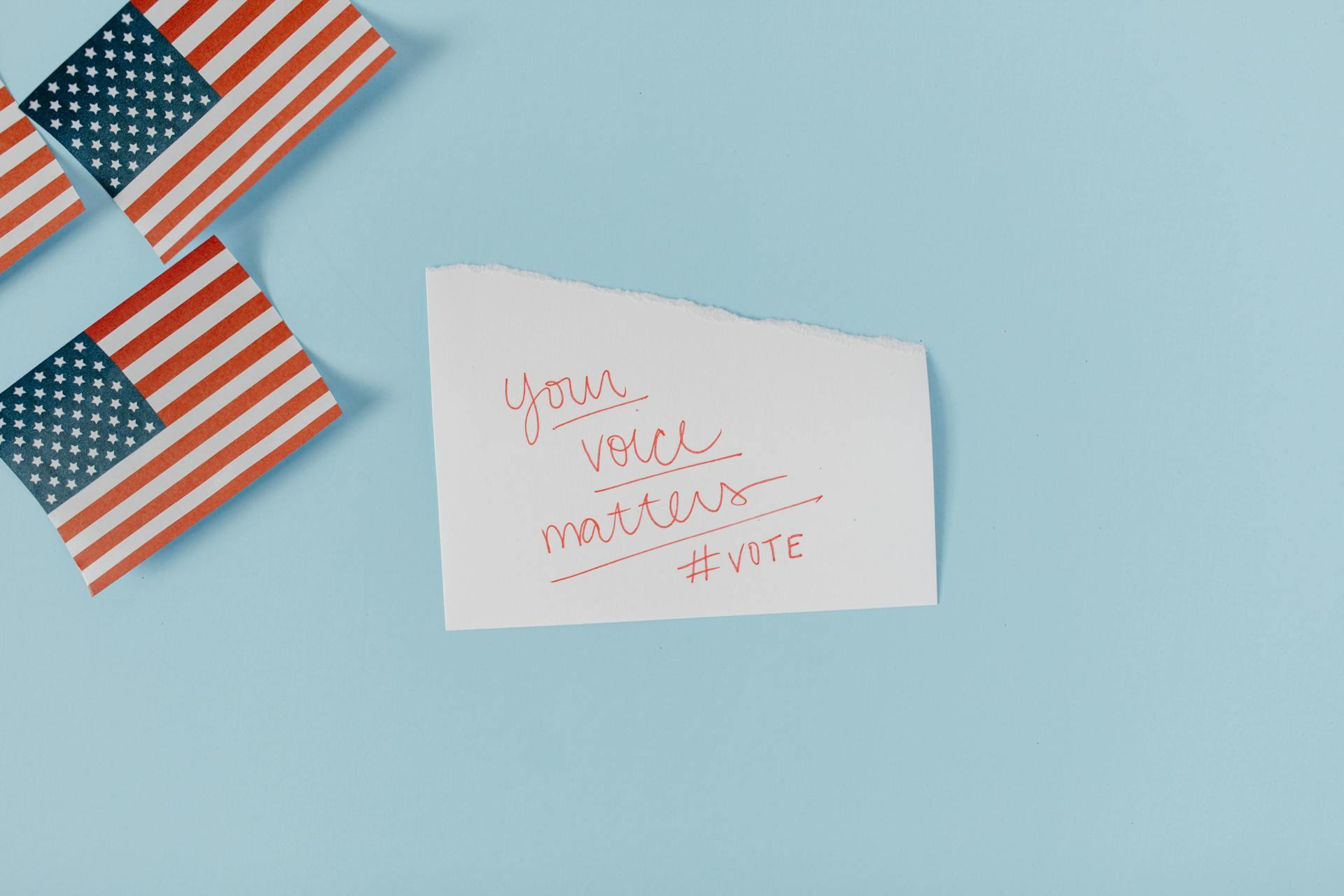 A handwritten note that says "Your voice matters #vote" near two small American flags