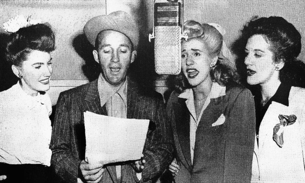 Black and white photo of Bing Crosby and the Andrews Sisters singing together