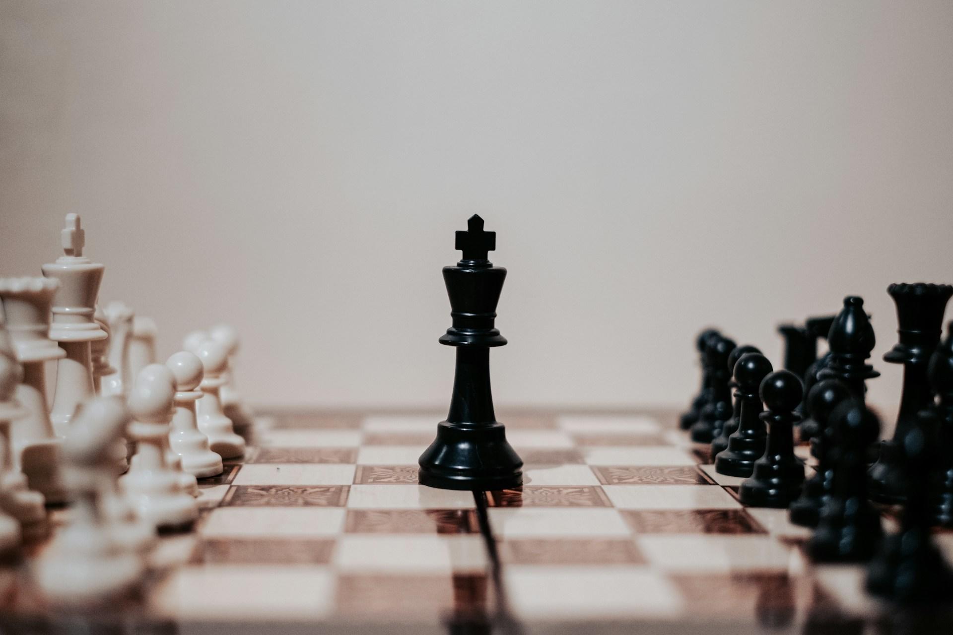 A chessboard with black and white chess pieces and the king in the middle.