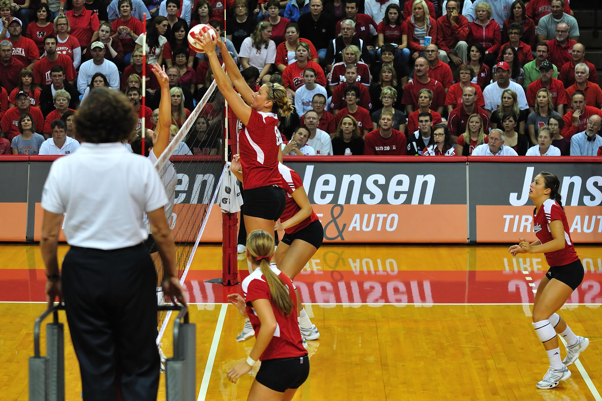The Nebraska volleyball team playing and blocking the volleyball.